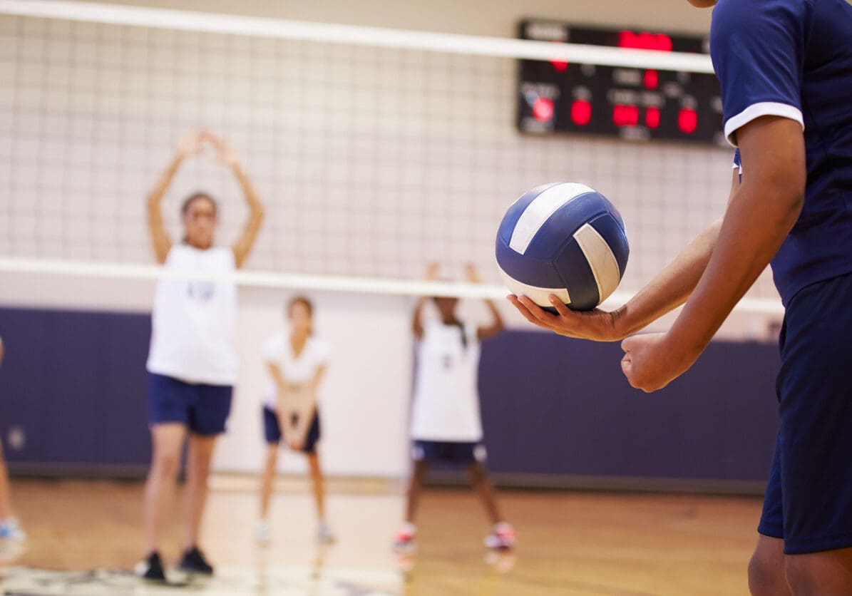 High School Volleyball Match In Gymnasium With Ball